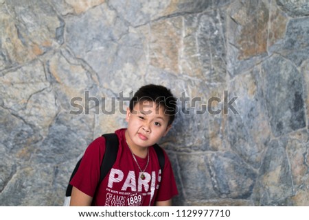 asian boy express silly face with brick wall background