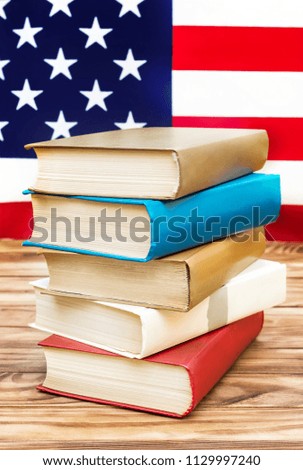 Stack of books on the table against american flag. American education. 
