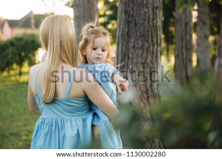 Young beautiful woman with her little cute daughter. Young daughter hugs mother in summer park
