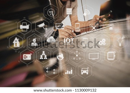 Internet of Things (IOT) technology with AR (Augmented Reality) on VR dashboard. designer hand working with digital tablet and laptop computer and book stack on wooden desk as concept