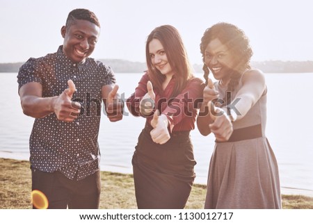 Group of friends having fun outdoors together. People relax and chat in the park on the shore of the lake.