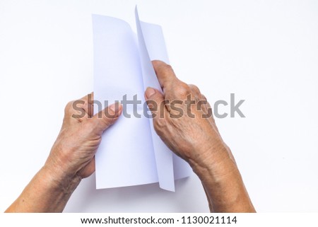 Senior woman's hand folding white paper on white background