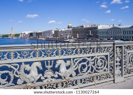 Ancient lace railing of the Annunciation bridge with the image of sea horses and a trident of Poseidon was made in 1850. Bridge over the Neva River on a summer sunny day in St. Petersburg in Russia.
