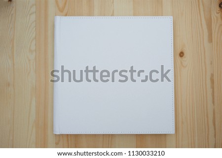 On the wooden surface is a closed book with a leather cover in white. The concept of education and science.