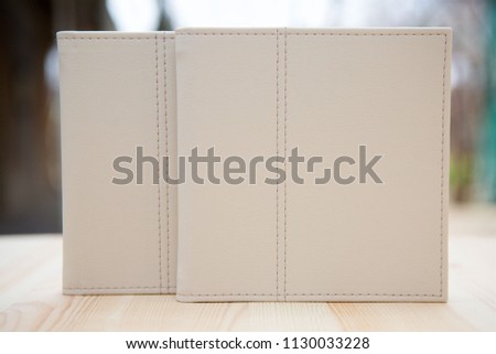 On the wooden surface are two closed books of the same size with a leather cover in white. The concept of education and science.