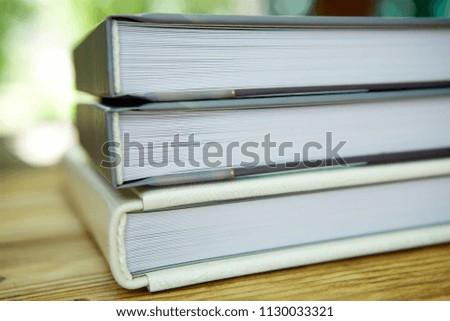 On the wooden surface is a stack of closed books of different thicknesses. The concept of education and science.