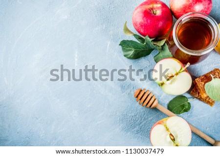 Jewish holiday Rosh Hashanah or apple feast day concept, with red apples, apple leaves and honey in jar, light blue background copy space above Royalty-Free Stock Photo #1130037479