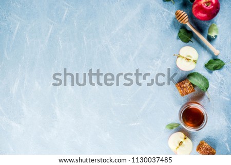 Jewish holiday Rosh Hashanah or apple feast day concept, with red apples, apple leaves and honey in jar, light blue background copy space above Royalty-Free Stock Photo #1130037485
