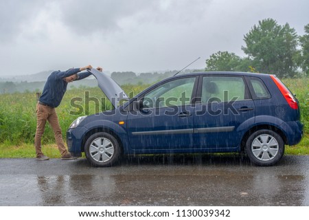 Car trouble in the rain. Broken car. Royalty-Free Stock Photo #1130039342