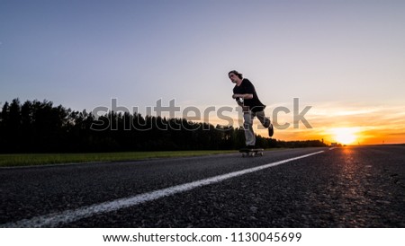 Skater make pushing on empty road at the beautiful sunset