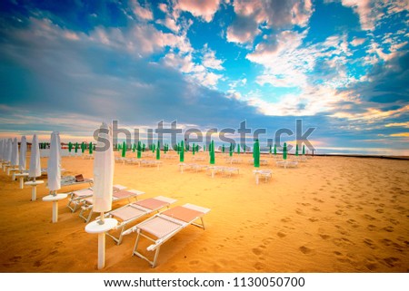 Empty beach with sun beds and umbrellas, sunset.