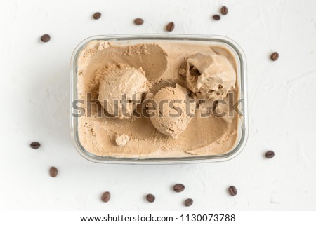 Scoop of coffee ice cream on white background, top view, copy space. Frozen coffee gelato, homemade ice cream - healthy summer dessert.
