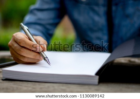 Young woman hand holding pen and reading book with copy space.