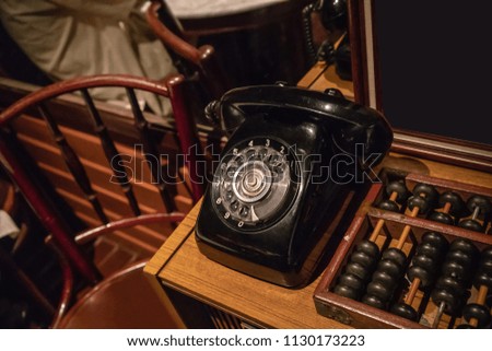 Black vintage phone on wooden table near vintage abacus.