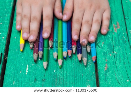 colorful pens and child hand on the green wooden table for school activity time or education concept.creative ideas for child development.