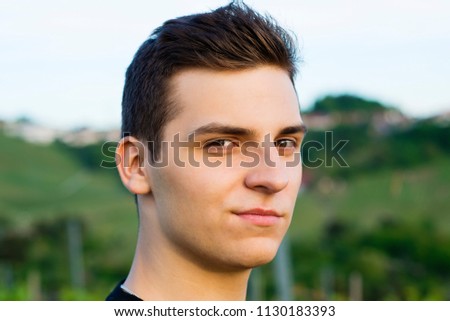 Young adorable man model with a smirk looks into the camera in the evening