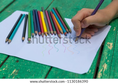 the child draw picture with colorful pens on the wooden green table in the nursery or school for activity concept. creative ideas for child development.