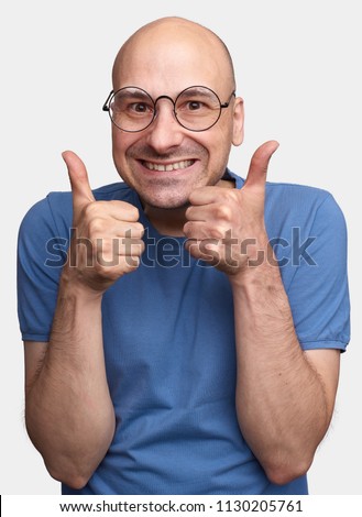 Happy middle aged caucasian bald man wearing eyeglasses and t-shirt making thumb up sign and smiling cheerfully