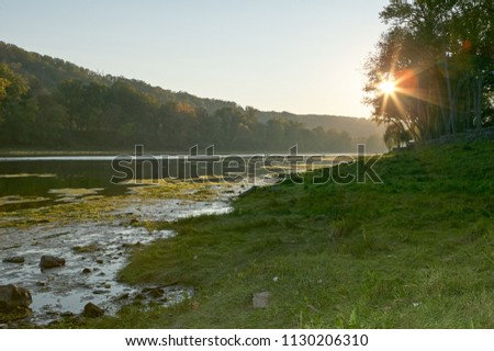 Star burst sun over the White River, Arkansas with early morning mist in a tranquil scenic landscape Royalty-Free Stock Photo #1130206310