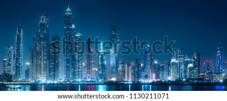 Modern buildings of Dubai Marina bay with lights at night on background, view from Palm Jumeirah, UAE Royalty-Free Stock Photo #1130211071