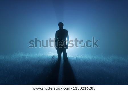 A foggy night. Blue tones. Silhouette of a man. Spotlight behind a man Royalty-Free Stock Photo #1130216285