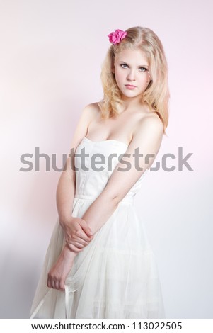Picture of a fashion young beautiful girl with blonde hair wearing a white dress over pink