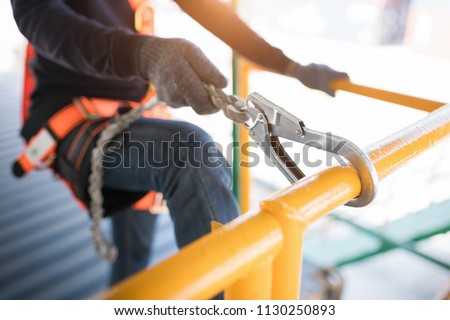 Construction worker wearing safety harness and safety line working at high place Royalty-Free Stock Photo #1130250893