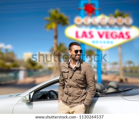 road trip, travel and people concept - happy man near convertible car over welcome to fabulous las vegas sign background