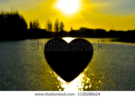 black heart shaped symbol on morning golden lake surface sunlight water as background