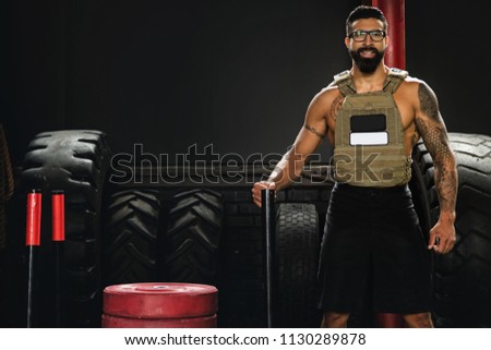 Happy sportsman wearing weight vest during his workout in the gym