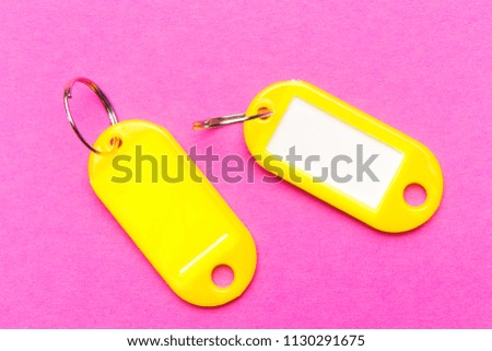 Yellow key tag on purple cardboard textured background.The concept of renting, selling. Template. Trend colors