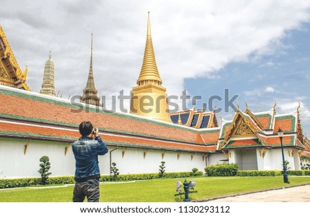 Young Asian traveling backpacker taking photos in Wat Phra Kaew in Bangkok, Thailand