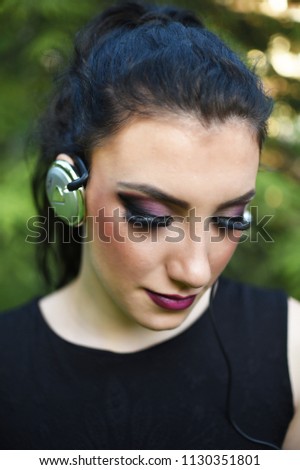 Girl with headphones. Pretty girl listening music with her headphones in the park