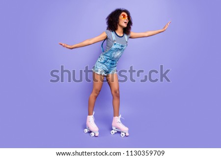 Full body portrait of positive funky girl learning to ride on roller skates keeping balance enjoying activity isolated on bright violent background retro vintage quad student concept