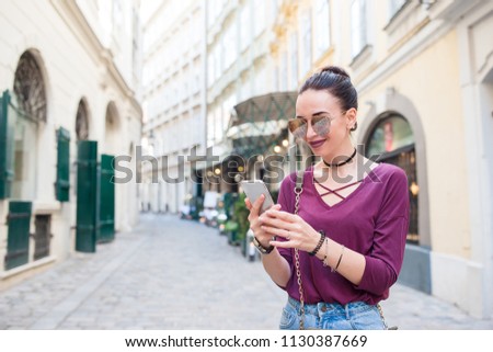 Happy woman with smartphone in european street. Young attractive tourist outdoors in Vienna city