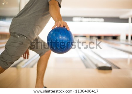 Man with blue bowling ball throwing to a bowling alley