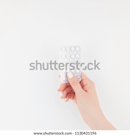 Woman hand with pastel manicure polish holding pills in blister isolated on white background with copy space. Square Template for feminine beauty blog social media. Female healthcare concept