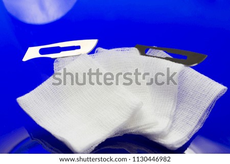 Medical swabs and surgical knifes on blue background