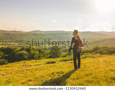 back view of young man with photo camera dslr on the mountain summer field