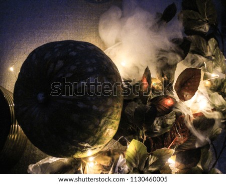 Night Helloween composition with pumpkin, leaves and smoke.Warm and cold light.Autumn