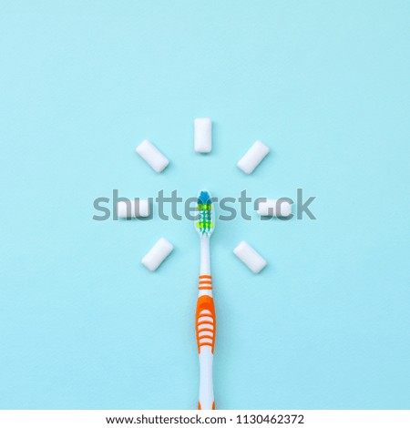 Toothbrush and chewing gums lie on a pastel blue background. Top view, flat lay. Minimal concept