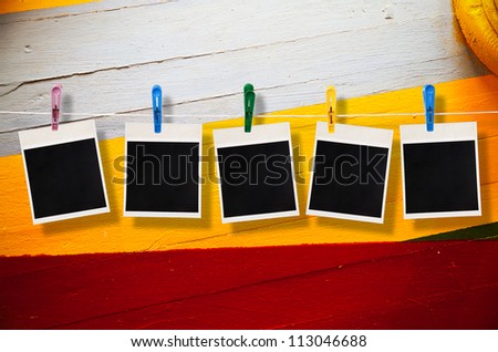 Blank picture frame hanging on clothesline on wood background