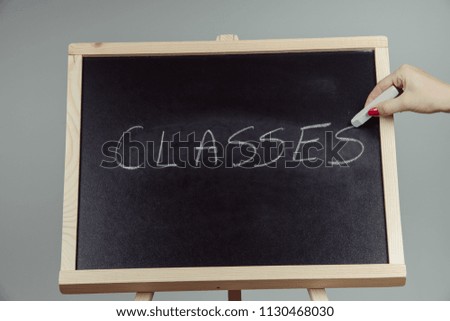 Classes written in white chalk on a black chalkboard . gray background