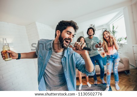 Group of friends playing karaoke at home. Concept about friendship, home entertainment and people Royalty-Free Stock Photo #1130502776
