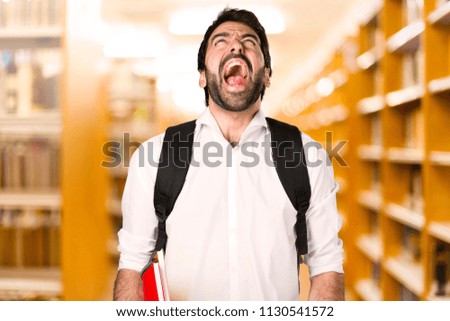 Student man shouting on defocused library