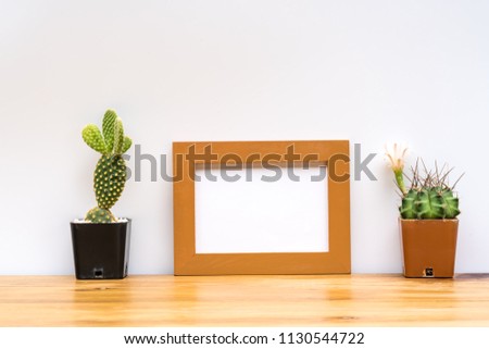 Beautiful  cactus  and  wooden  picture
frame  on  wood  table  on  white  isolate
background.