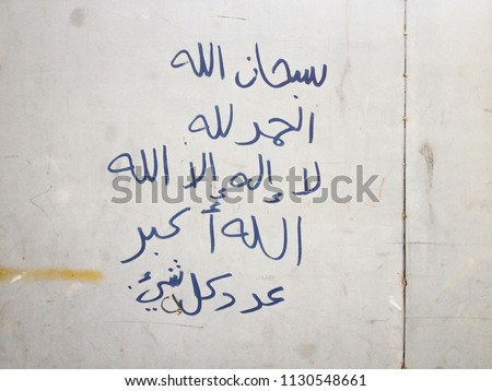 Hand writings on dirty steel wall, by Arabic language, its mean “"God is perfect”, “thank God”, “There is no god but Allah” and “Allah is Great”.