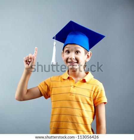 Portrait of happy boy pointing upwards on grey background