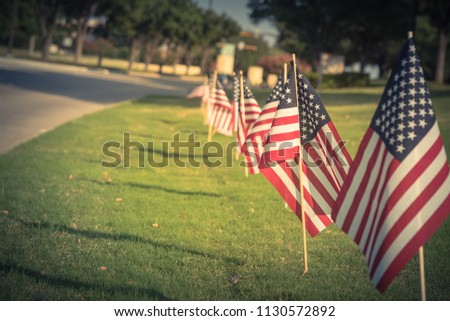 Vintage tone long row of lawn American Flags on green grass yard blow in the wind. Groups of flying USA flags at an business park along street. Independence Day celebration in Plano, Texas, USA