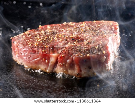 Grilled sirloin steak on hot iron plate Royalty-Free Stock Photo #1130611364